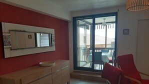 Un salon moderne avec un meuble en bois, un grand miroir et un fauteuil rouge.