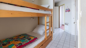 A bunk bed room with a colorful blanket, a white pillow, and a small wall-mounted light fixture. - Mimizan Beach: 6-person apartment with balcony and parking (Mimizan)