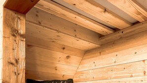 Une pièce aménagée comme une cabane en bois, avec un lit, un oreiller orné d’un motif de cerf et une tête de lit en bois.