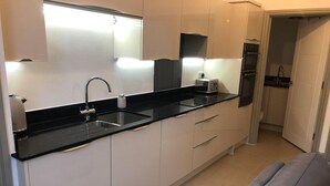 A modern kitchen with a black countertop, white cabinets, a built-in oven, and a toaster. - Smithy Bungalow, Free Private Parking (Buxton)