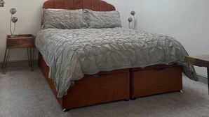 A bedroom with a skylight, a bed with a red headboard, a bedside table, and a wall-mounted artwork. - Smithy Bungalow, Free Private Parking (Buxton)