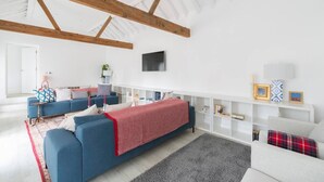 Ein modernes Wohnzimmer mit einem blauen Sofa, einer roten Decke und einem grauen Teppich.