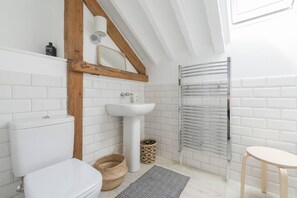Features a minimalist bathroom with a white toilet, pedestal sink, and mirror.