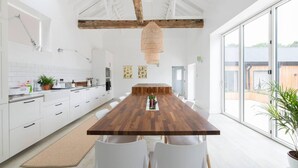 Eine moderne Küche mit weißen Schränken, einem Holztisch und einem großen Fenster.