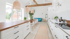Eine moderne Küche mit weißen Schränken, einer Holz Arbeitsplatte und einem großen Fenster, das für natürliches Licht sorgt.