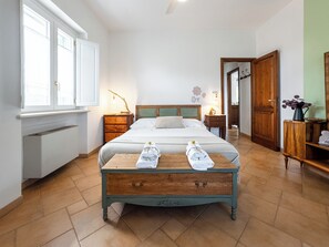 A bedroom with a bed, bedside tables, a wooden dresser, a radiator, a window, and a door. - Tale of Apulia - Selva di Fasano (Selva di Fasano)