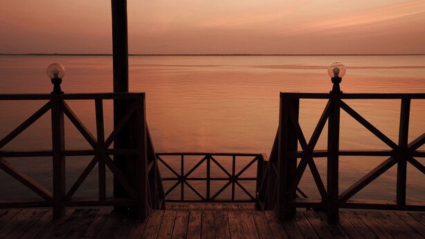 A wooden deck with railings and a view of the water. - Kidoti Bay (Kidoti)