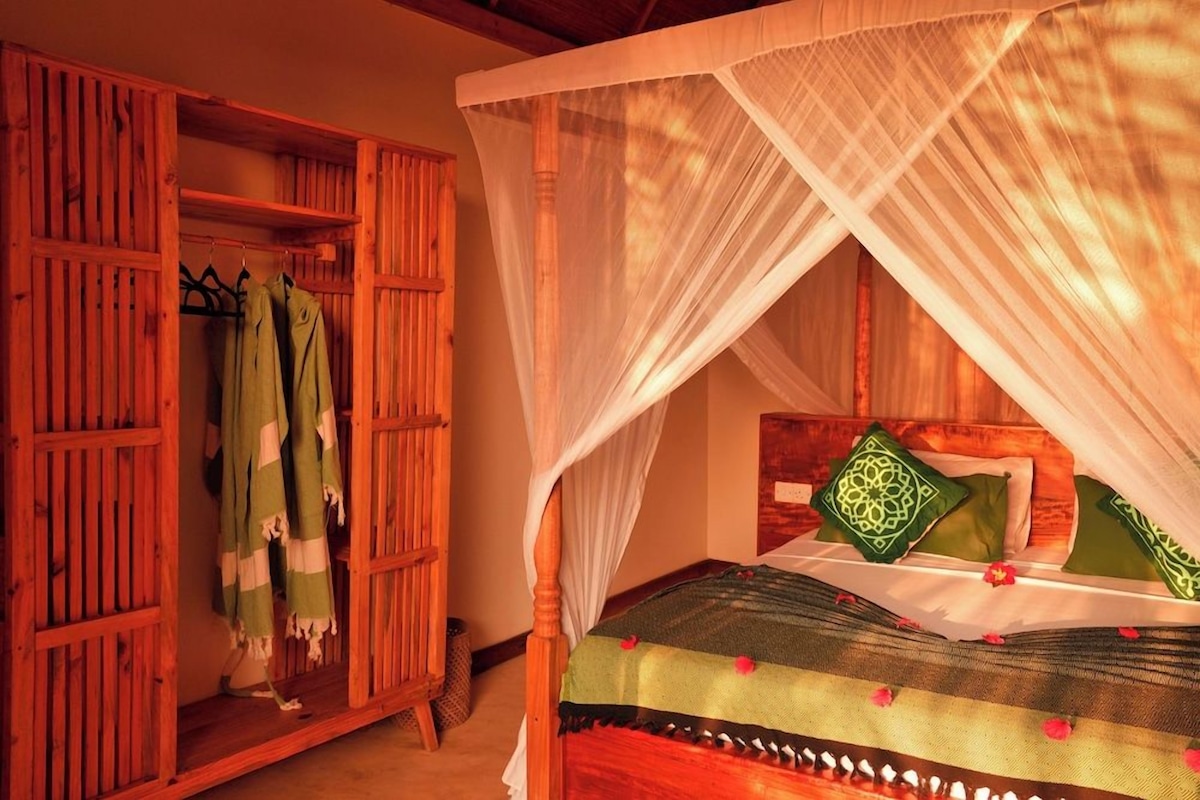 Una habitación con cama bajo dosel, un armario con ropa y una pared con panel decorativo.