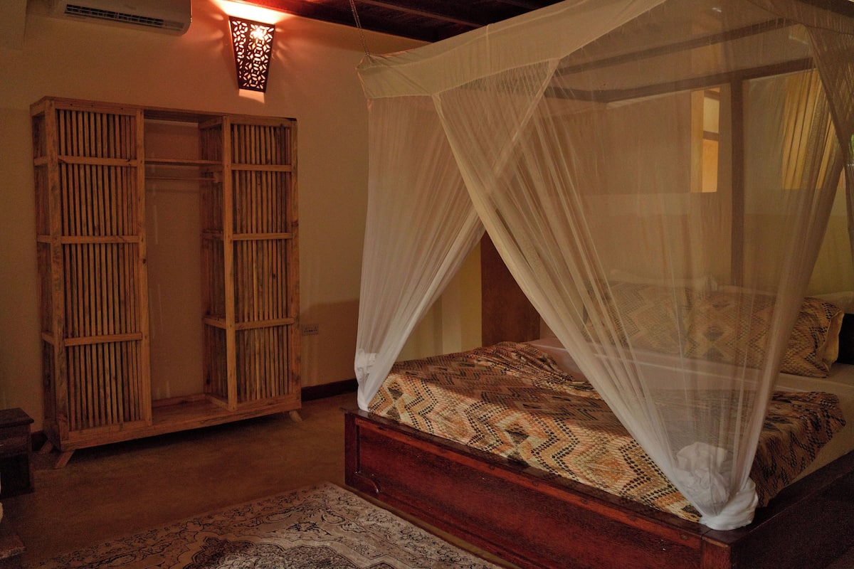 A bedroom with a wooden bed, a canopy bed, and a wardrobe with sliding doors.