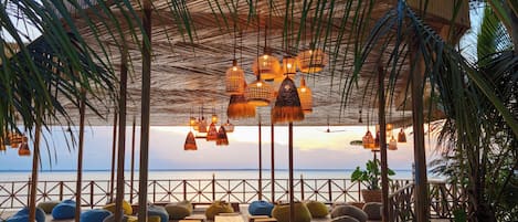 Una terraza de madera con asientos y vista al mar.