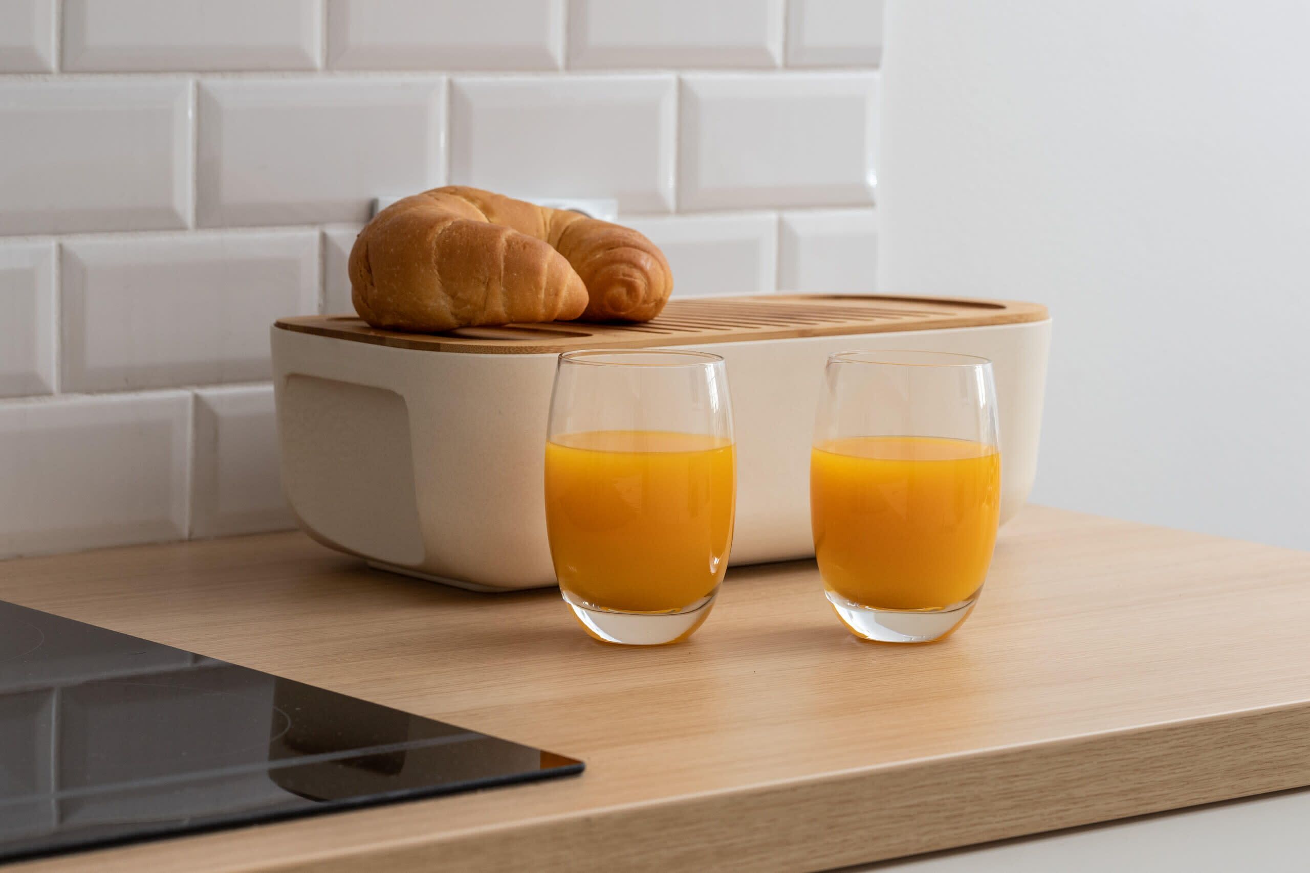 A breakfast setup with a croissant and two glasses of orange juice on a wooden table.