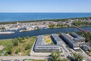 Vue aérienne d’une ville côtière, avec un grand complexe de bâtiments comprenant plusieurs niveaux de stationnement et une marina.
