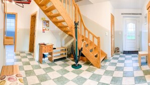 A spacious hallway with a wooden staircase, a small desk, and a door leading to another room.