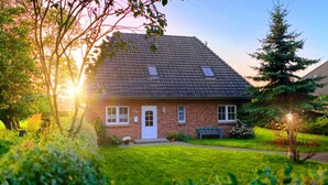A brick house with a tiled roof, a front porch, and a well-maintained lawn.