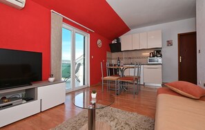 Un espace de vie compact comprenant un téléviseur, un coin repas et une kitchenette.