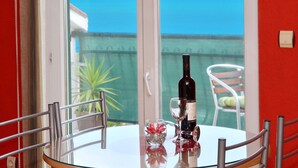 Une table avec une bouteille de vin et un verre, une fleur dans un vase en verre, et une chaise.