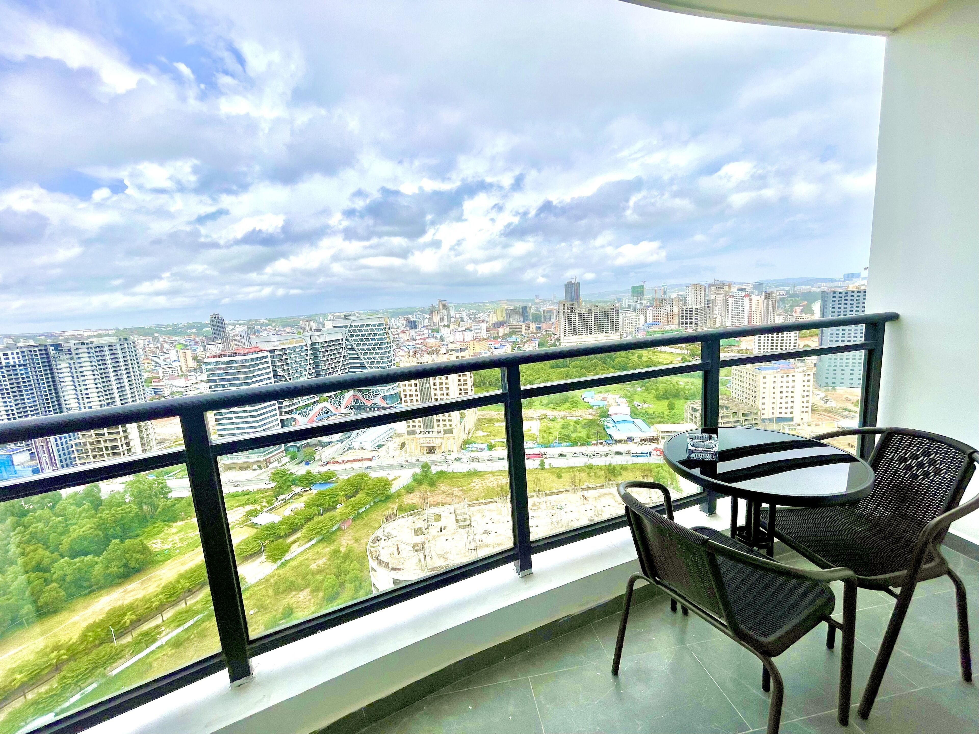 Ein Balkon mit Blick auf eine Stadtansicht, einem Tisch und zwei Stühlen.