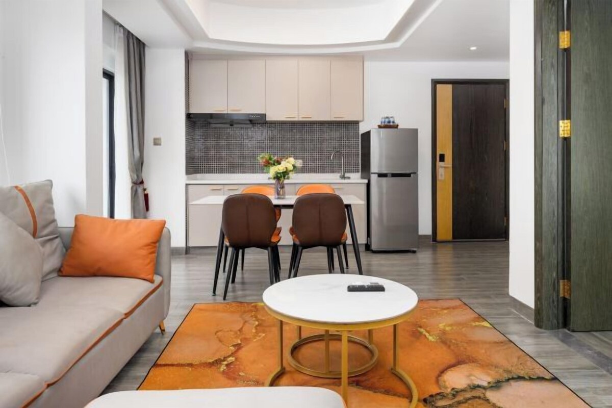 A modern living room with a sofa, a coffee table, and a dining area with chairs and a table.