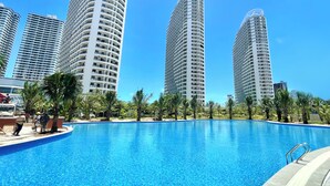 A swimming pool surrounded by tall residential buildings, with clear skies above. - Star Bay Residence (Sihanoukville)