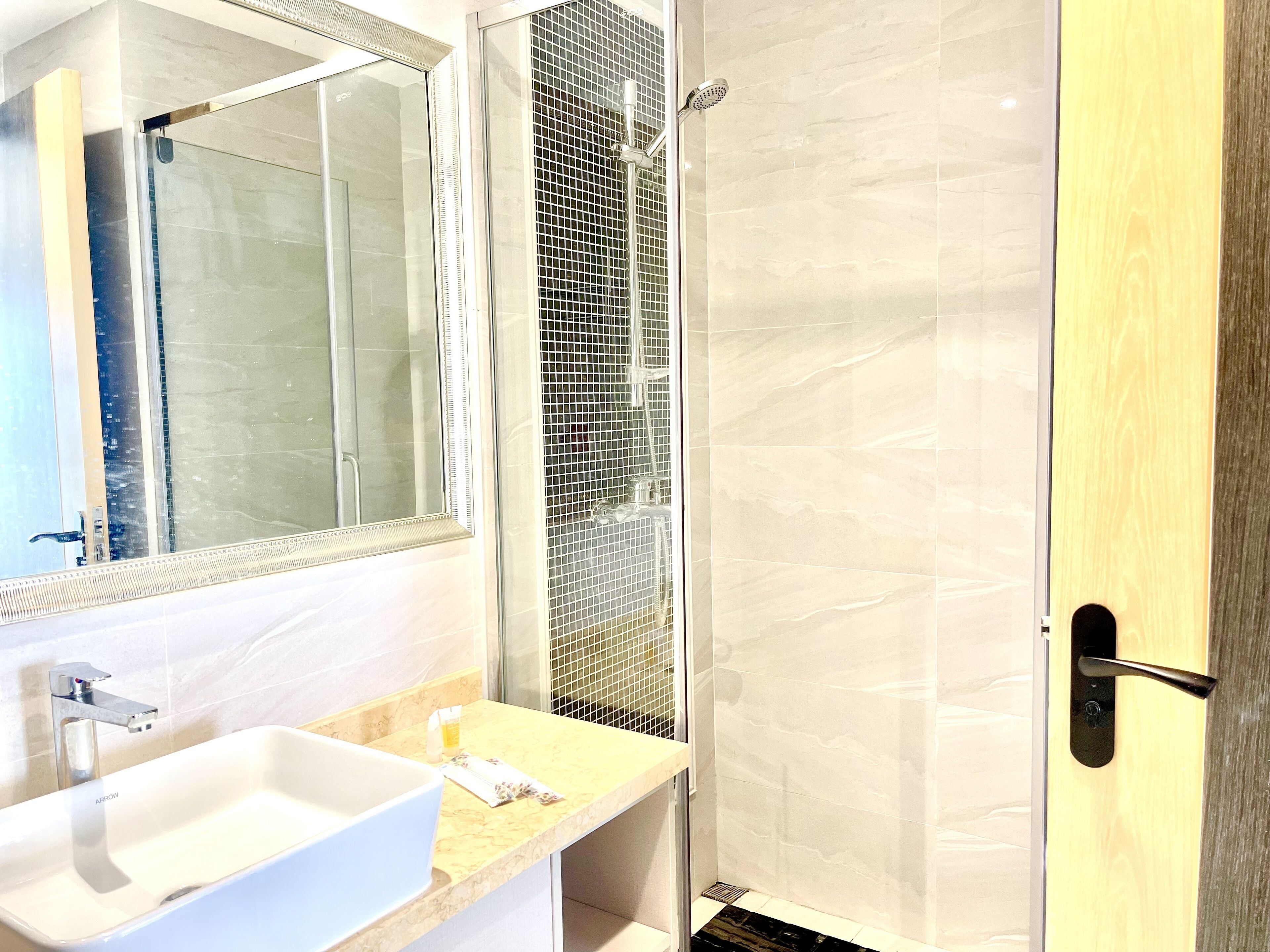 Un baño moderno con un espejo grande, un lavabo y un box de ducha.