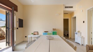A spacious dining area with a long table, a small side table with a plant, and a cabinet with drawers. - 3294 Villa Dolce Grazia by Barbarhouse (Manduria)
