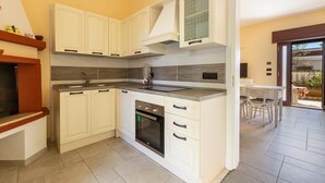 A modern kitchen with white cabinetry, a built-in oven, and a dining area with a table and chairs. - 3294 Villa Dolce Grazia by Barbarhouse (Manduria)