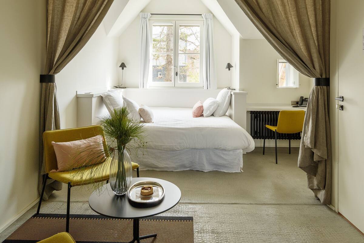 A bedroom with a bed, a desk, a chair, and a window.