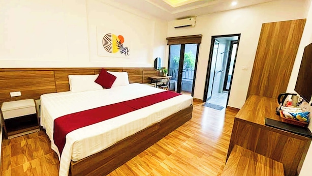 A hotel room with a large bed, wooden flooring, a desk, and a view of the outdoors. - BAI CHAY PANDA HOTEL (Bai Chay)