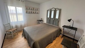 A bedroom with a large bed, a desk with a lamp, a chair, and a window with curtains. - Seafront apartment, Rosas AV 06 (Rosas / Roses)