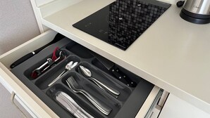 A kitchen with a built-in induction cooktop and a drawer organizer with utensils. - Dream Apartments Batumi (Batumi)