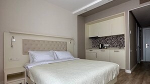 A bedroom with a bed, bedside table, and a built-in kitchenette with cabinets and a tiled backsplash. - Dream Apartments Batumi (Batumi)