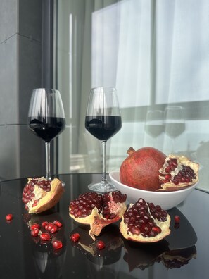 Une table avec deux verres à vin, un bol de grenades et une grenade coupée en deux.
