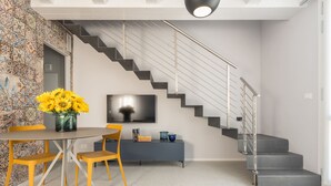 Un intérieur moderne avec un escalier, un coin repas comprenant une table et des chaises, et un téléviseur à écran plat fixé au mur.