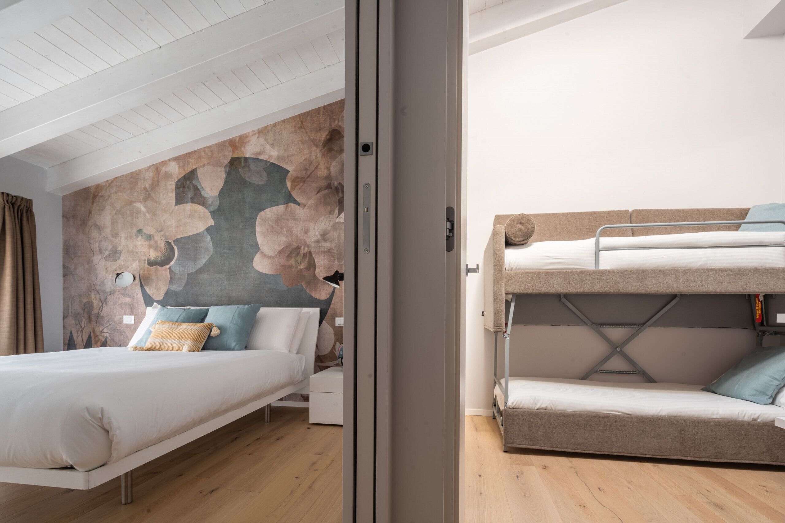 Un dormitorio moderno con una cama litera y una cama individual, ambas con ropa de cama blanca.
