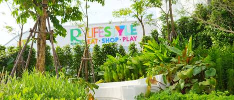 A lush garden with a sign reading "LIFESTYLE" and "eat, shop, play".