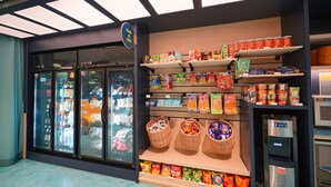 Ein Supermarkt mit Kühlregalen, Regalen voller Snacks und einer Selbstbedienungsgetränkemaschine.