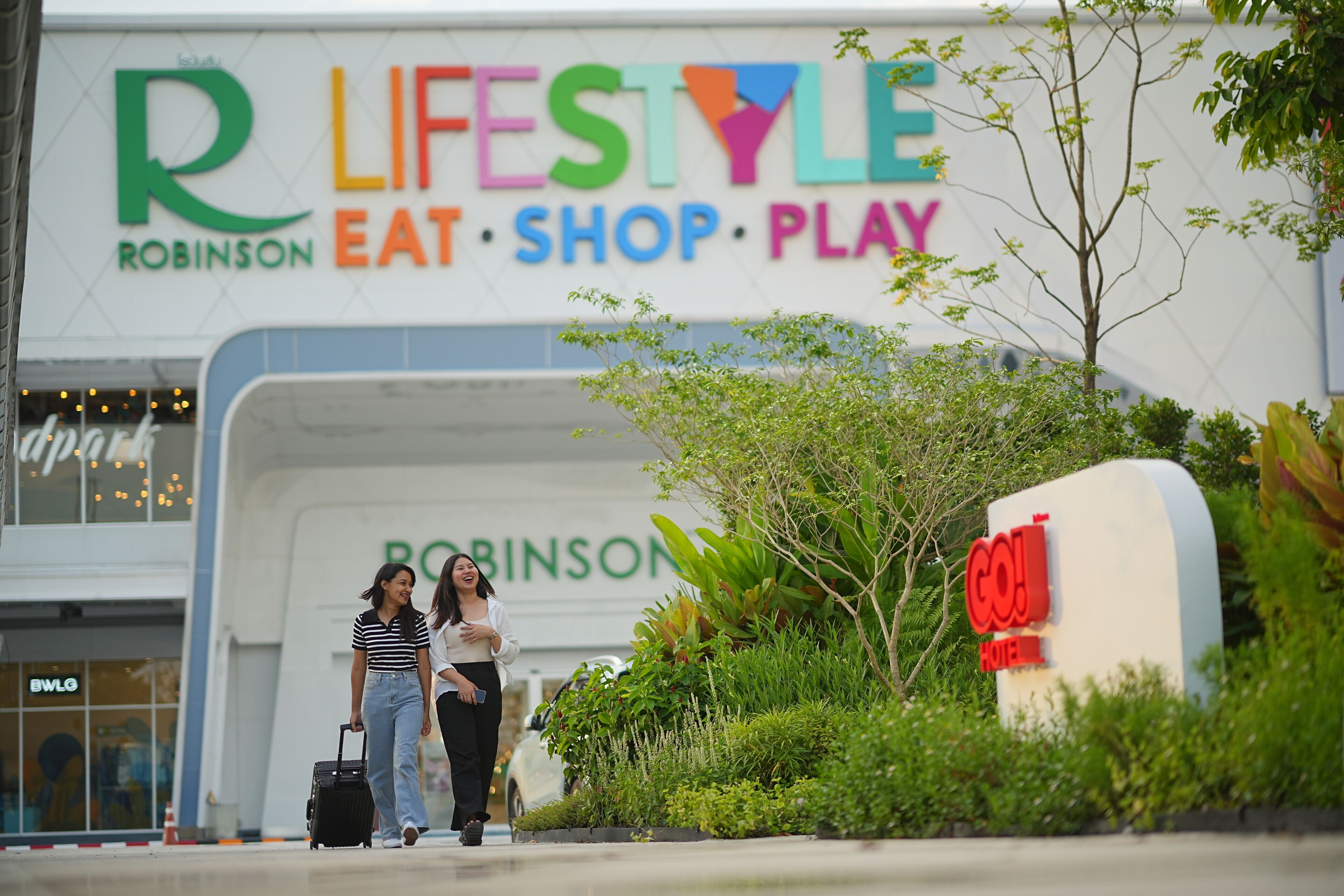 A sign for 'R LIFESTYLE Robinson Eat Shop Play' with a 'Goji Hotel' sign nearby.