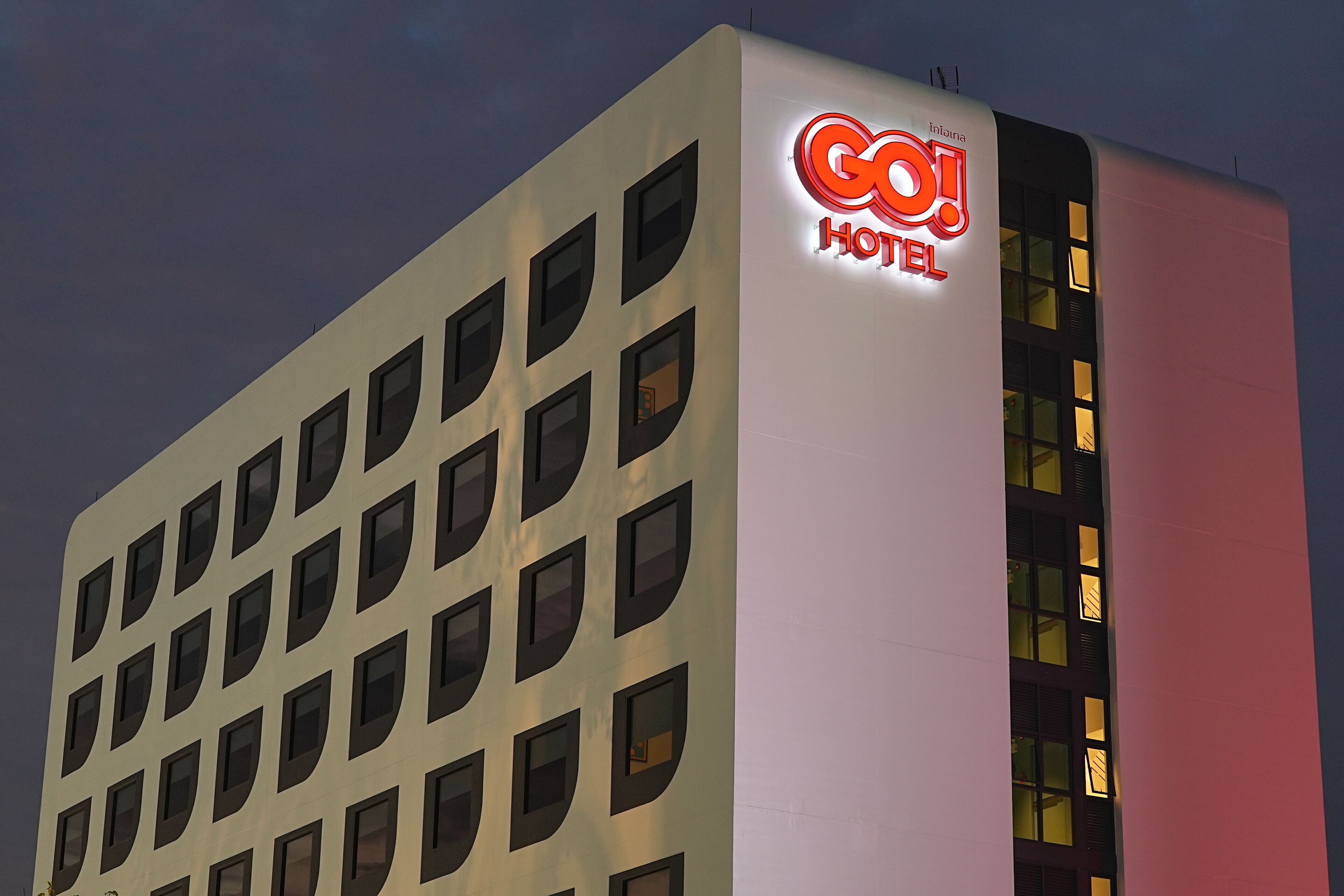 Ein Hotelgebäude mit einem gut sichtbaren Schild mit der Aufschrift „GO! HOTEL“ und zahlreichen Fenstern.