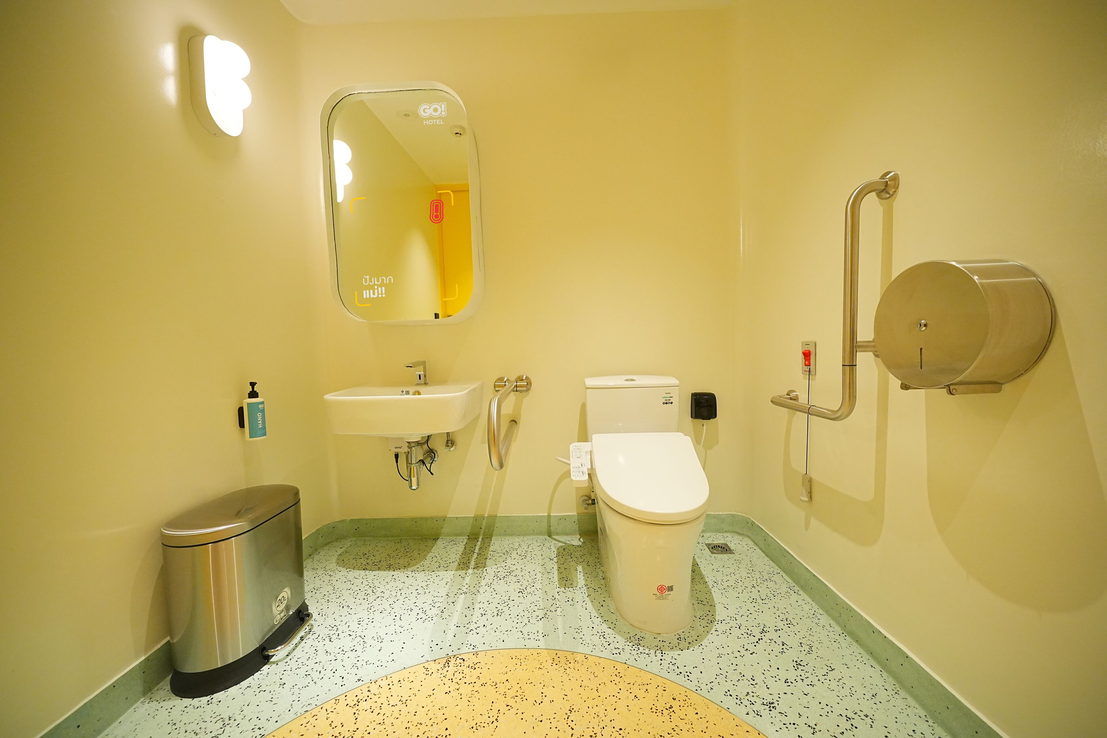 Un baño con lavamanos, inodoro, cubo de basura y espejo.