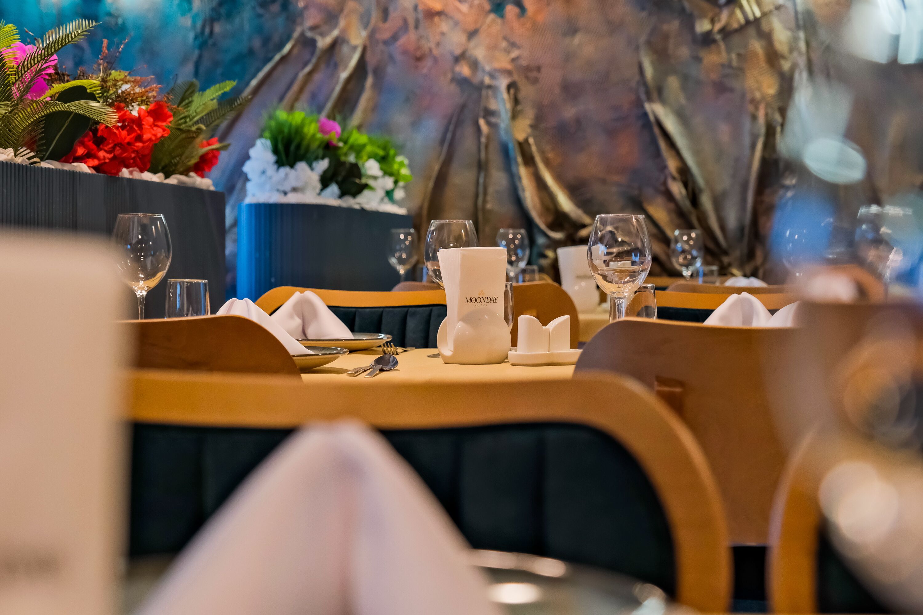 A dining table set with white napkins, wine glasses, and a menu holder labeled "MOONDAY".