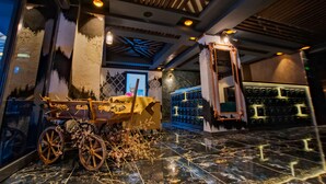 Un vestíbulo con un carruaje antiguo, un muro decorativo y una lámpara moderna.