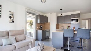 Una cocina moderna con armarios grises, una isla central y una zona de comedor con taburetes de bar.