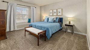 A bedroom with a bed, a bedside table, a lamp, a window with curtains, and a wall-mounted picture. - Perfect For Groups | Near The Village & Mall (Boise)
