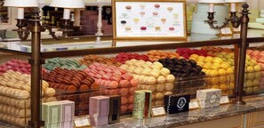 Et udvalg af macarons i forskellige farver bag en glasdisk med skilte på kasserne.