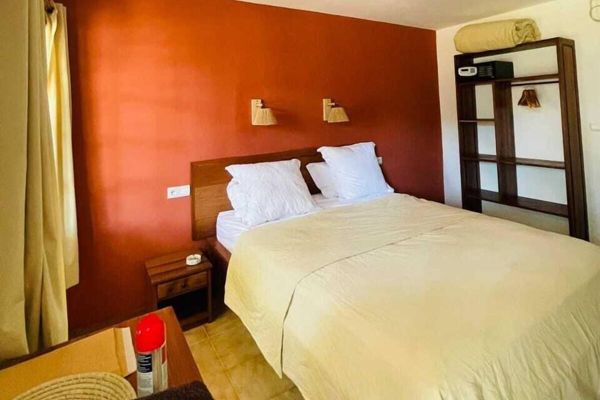 A hotel room with a bed, bedside table, lamp, and a wardrobe.