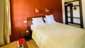 Ein Hotelzimmer mit einem großen Bett, einem Nachttisch, einer Wandlampe und einem Wandregal.