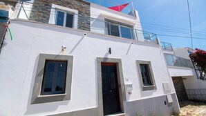 Un bâtiment à deux étages, doté d’une façade blanche, d’une porte noire et d’une petite fenêtre au rez-de-chaussée.