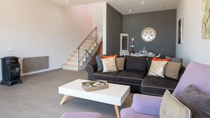 Un salon moderne comprenant un canapé, une table basse, une cheminée et un escalier.