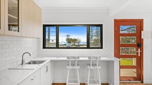 A kitchen with white cabinets, a sink, and a window overlooking a parking area.