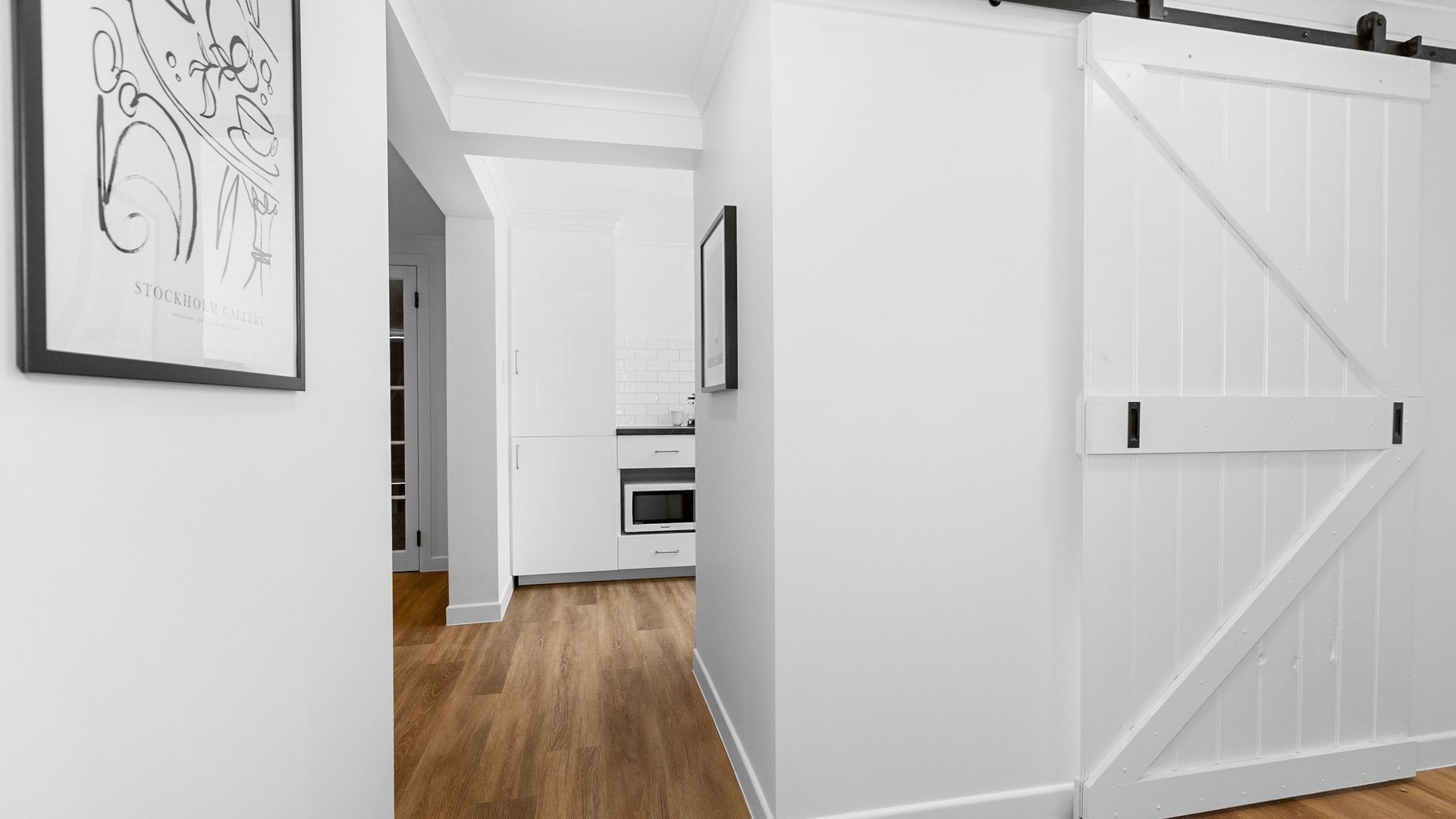 Une cuisine moderne avec des armoires blanches, un four à micro-ondes et un plancher en bois.